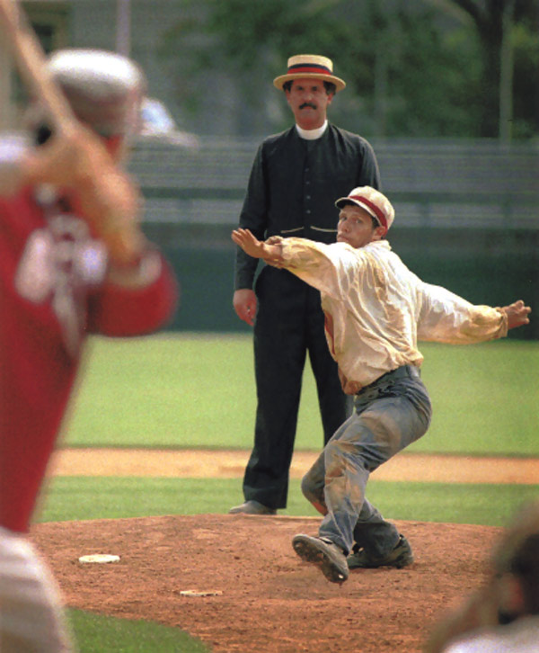 Vintage baseball photo: June 12, 1998: Eric “Express” Miklich pitching for the Brooklyn Atlantics (NY) in an 1887 match against the Glen Head Zig Zags (NY) on Doubleday Field in Cooperstown, New York.  The Umpire, Gary Monti, is stationed behind the pitcher allowing him a better view to call plays occurring at the bases.  This practice was first instituted by one of the best 19th century umpires, former player “Honest” John Gaffney.  On April 18, 1888, opening day of the American Association season, Gaffney called balls and strikes from behind the pitcher while runners were on base and stood behind the catcher when there were no men on base. Photo by Tom Ferrara.  Click photo to return to previous page.